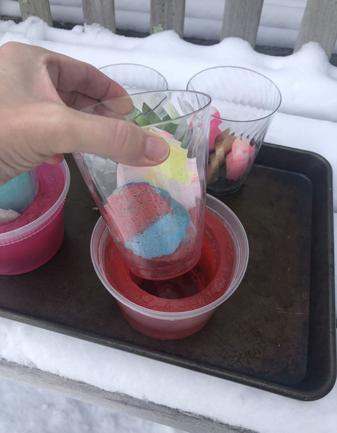 Préparez de simples votives à glace en congelant de l'eau pendant la nuit dans un contenant de charcuterie et en ajoutant du colorant alimentaire.  Un bel ajout à votre fête pandémique en plein air!