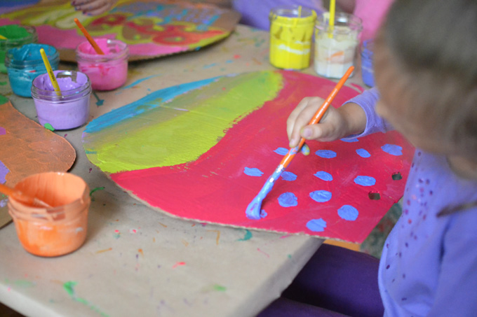 Mélanger les couleurs de peinture à l'aide de peintures à la détrempe pour peindre des beignets géants en carton.