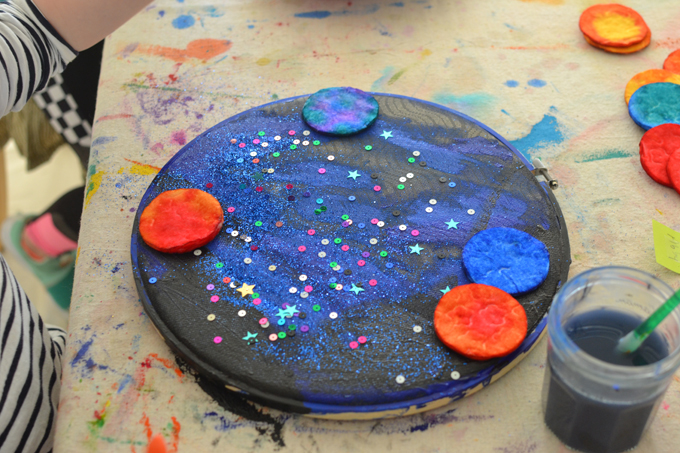Réalisez un système solaire avec des rondelles de coton, de l'aquarelle, de l'acrylique, du tissu et un cerceau à broder.  Une merveilleuse activité artistique ouverte pour célébrer le jour de la Terre!
