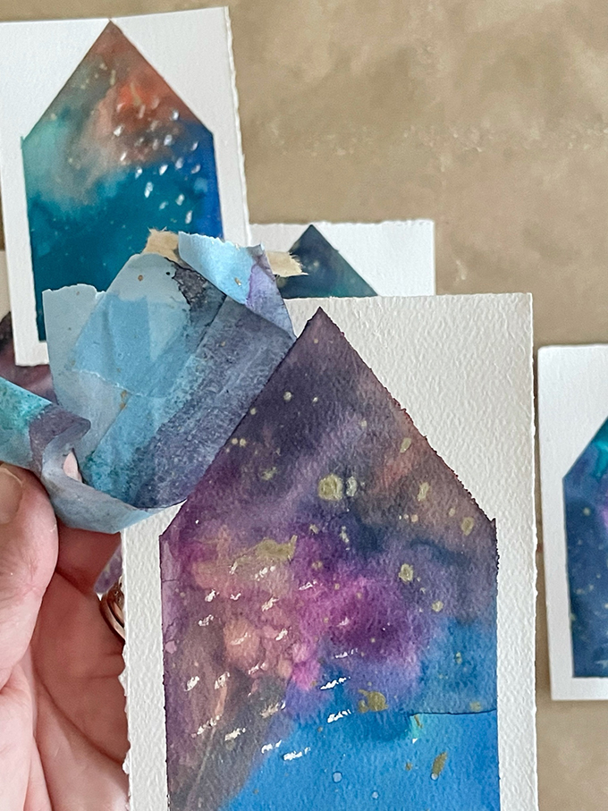 Fabriquez une guirlande de maison peinte en utilisant une technique d'aquarelle liquide et de ruban adhésif.