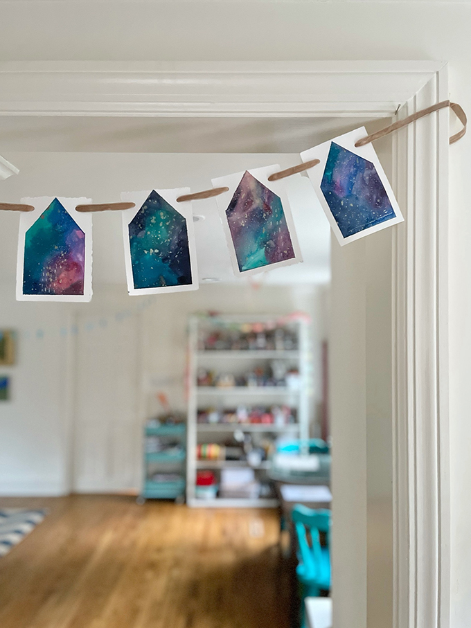 Fabriquez une guirlande de maison peinte en utilisant une technique d'aquarelle liquide et de ruban adhésif.