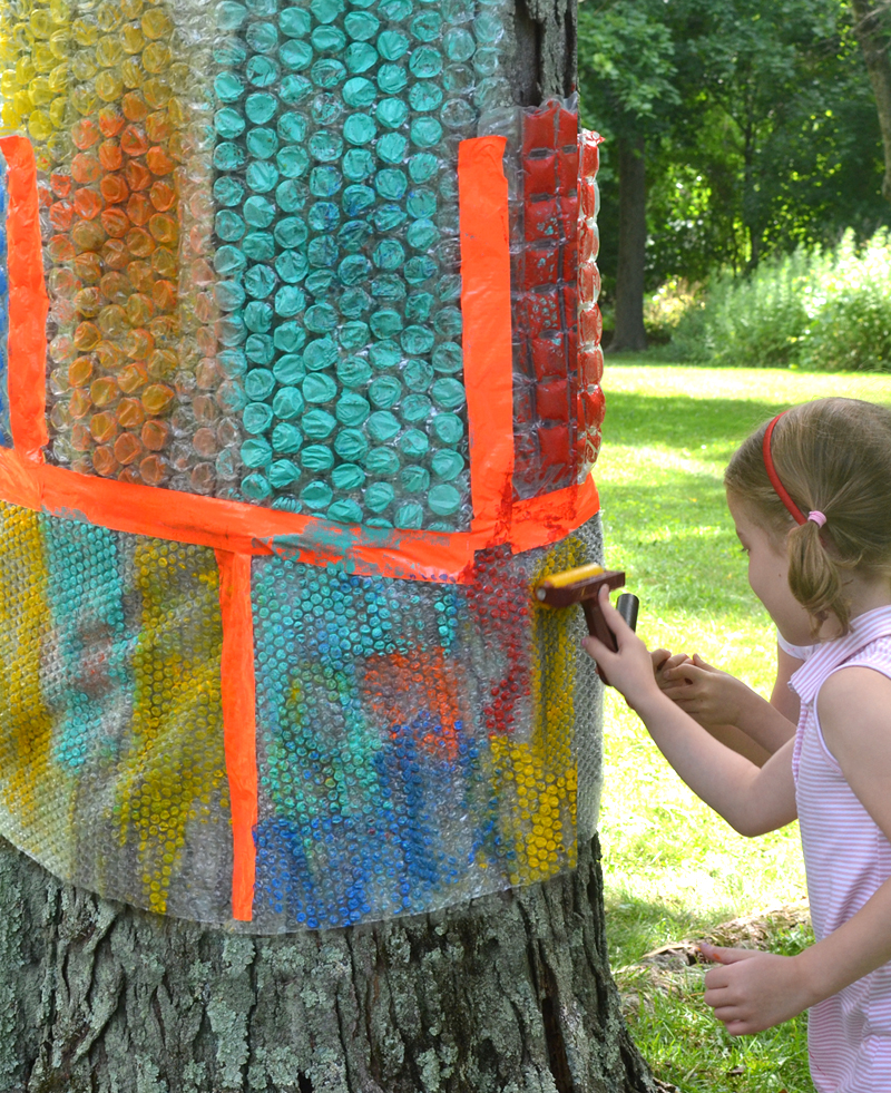 Enveloppez un arbre avec du papier babillage recyclé, donnez aux enfants des rouleaux et de la peinture, et laissez-les faire des impressions !