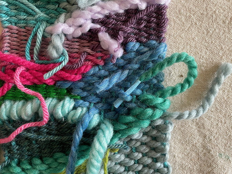 Rentrer les extrémités dans le dos d'un tissage de griffonnage coloré, réalisé avec un métier à tisser en carton