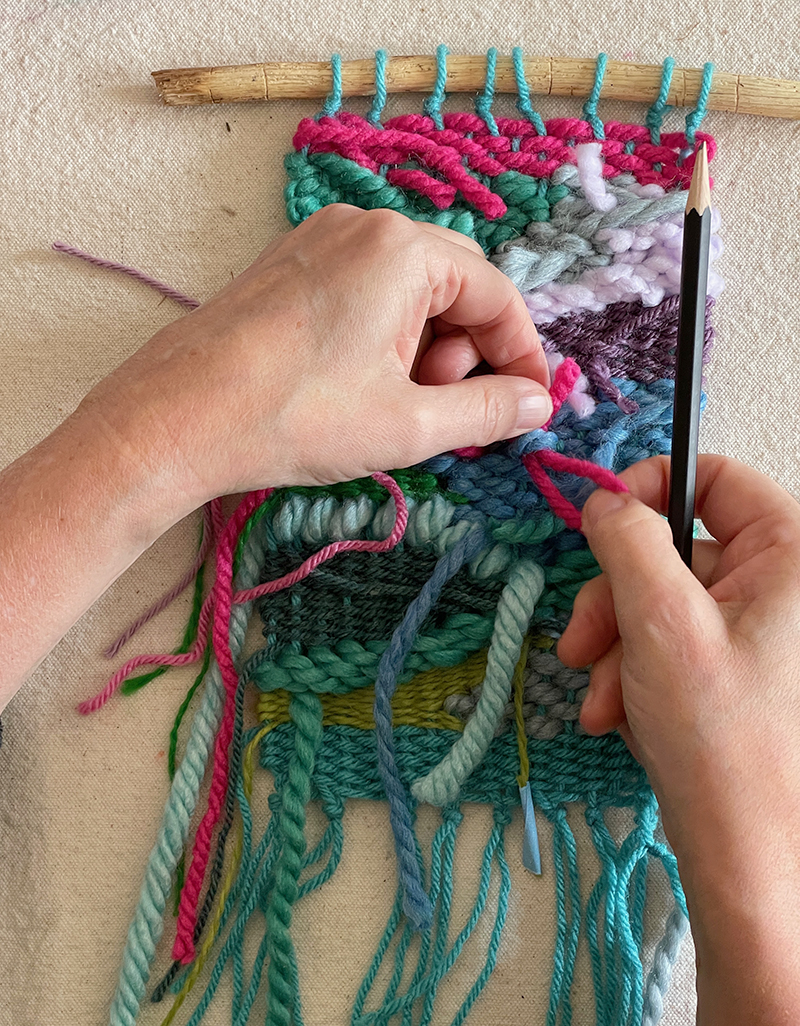 Rentrer les extrémités dans le dos d'un tissage de griffonnage coloré, réalisé avec un métier à tisser en carton