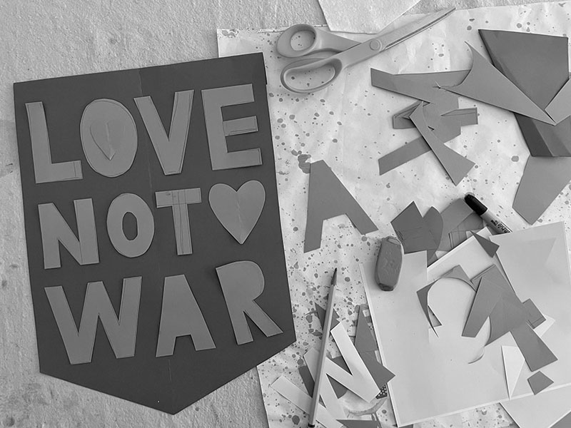 Découper des lettres sur du papier comme modèles à fabriquer "L'amour pas la guerre" bannières de vieilles chemises.