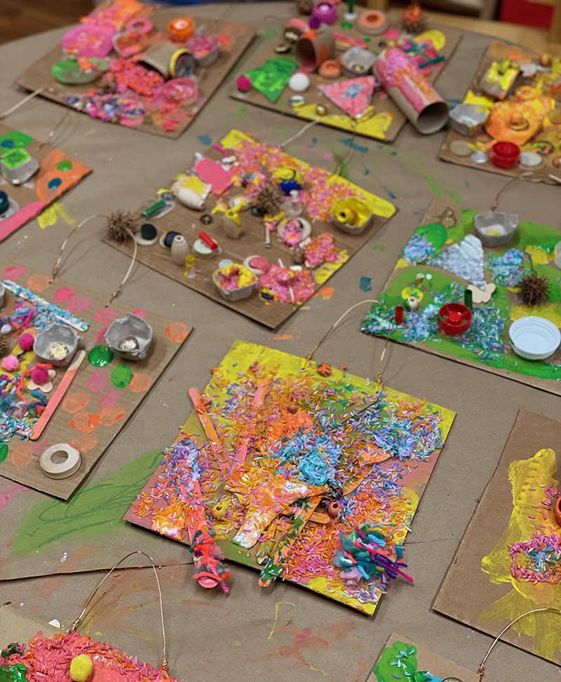 Toute une table de collages colorés et recyclés réalisés par des enfants d'âge préscolaire.