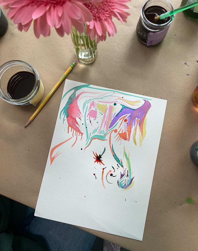 Peinture d'un adolescent jouant avec de l'aquarelle liquide à la table des natures mortes de fleurs.