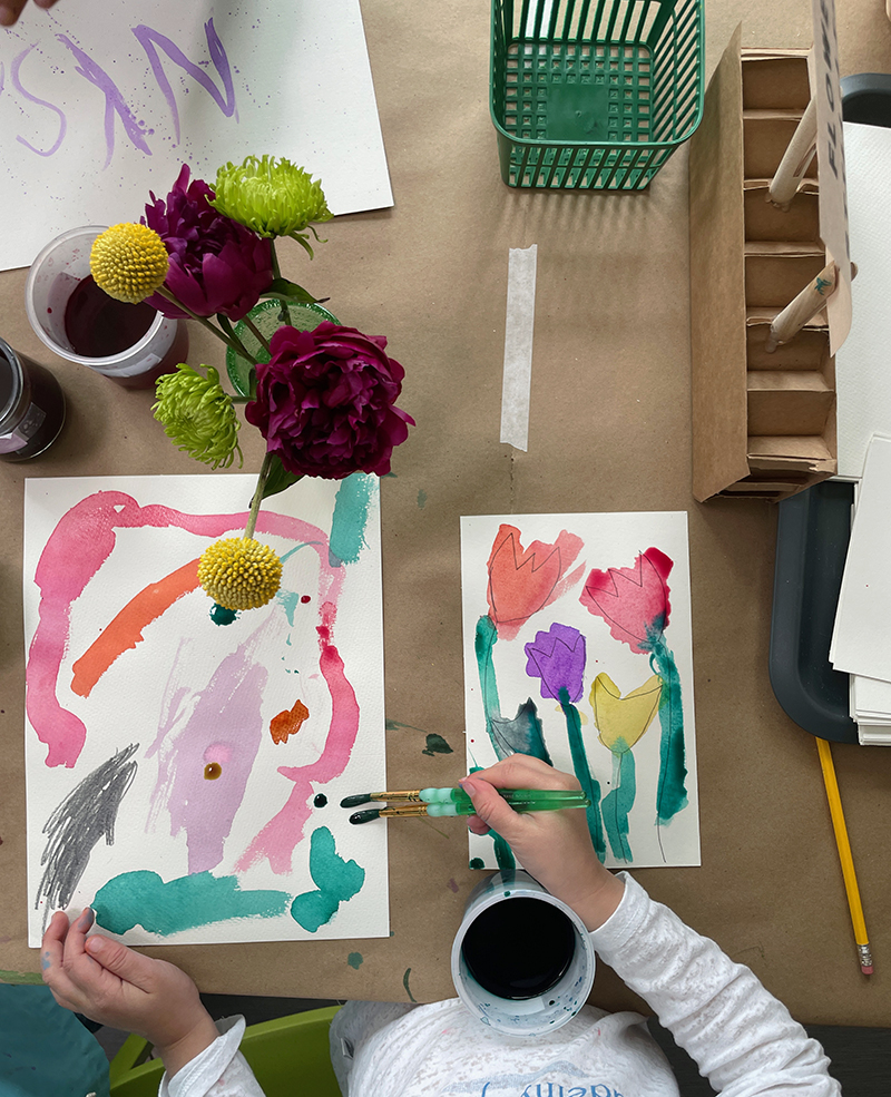 Le jeune enfant explore l'aquarelle liquide à la table de nature morte de fleurs.
